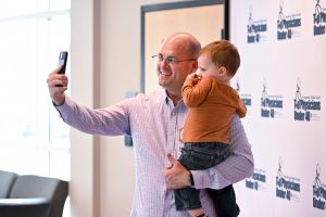 Dr. Kevin Rakszawski holds his young son as they take a "selfie" photo with a cellphone.