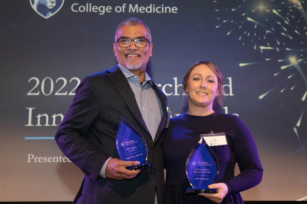 Sanjib Adhikary and Joan Gensamer stand beside each other holding their award trophies.