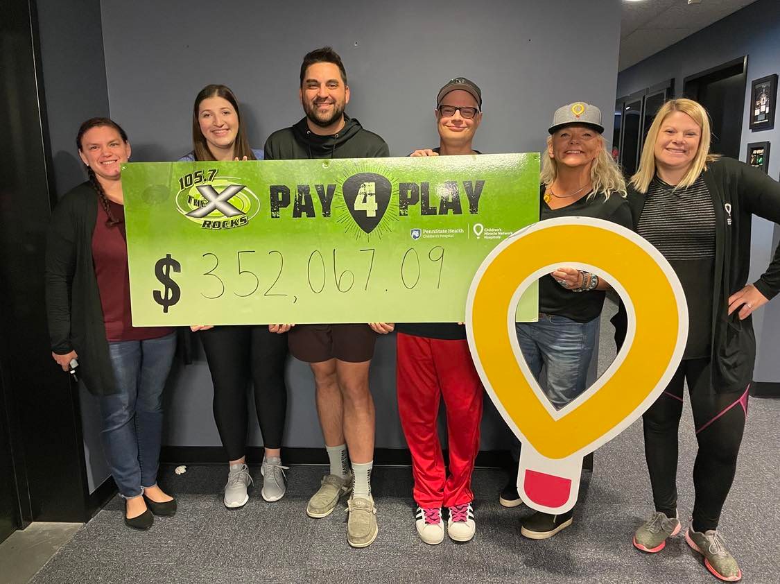 Six people pose with a large banner touting the amount of $352,067.09.