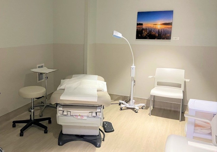 A clinic room with an exam chair, computer and various medical equipment.
