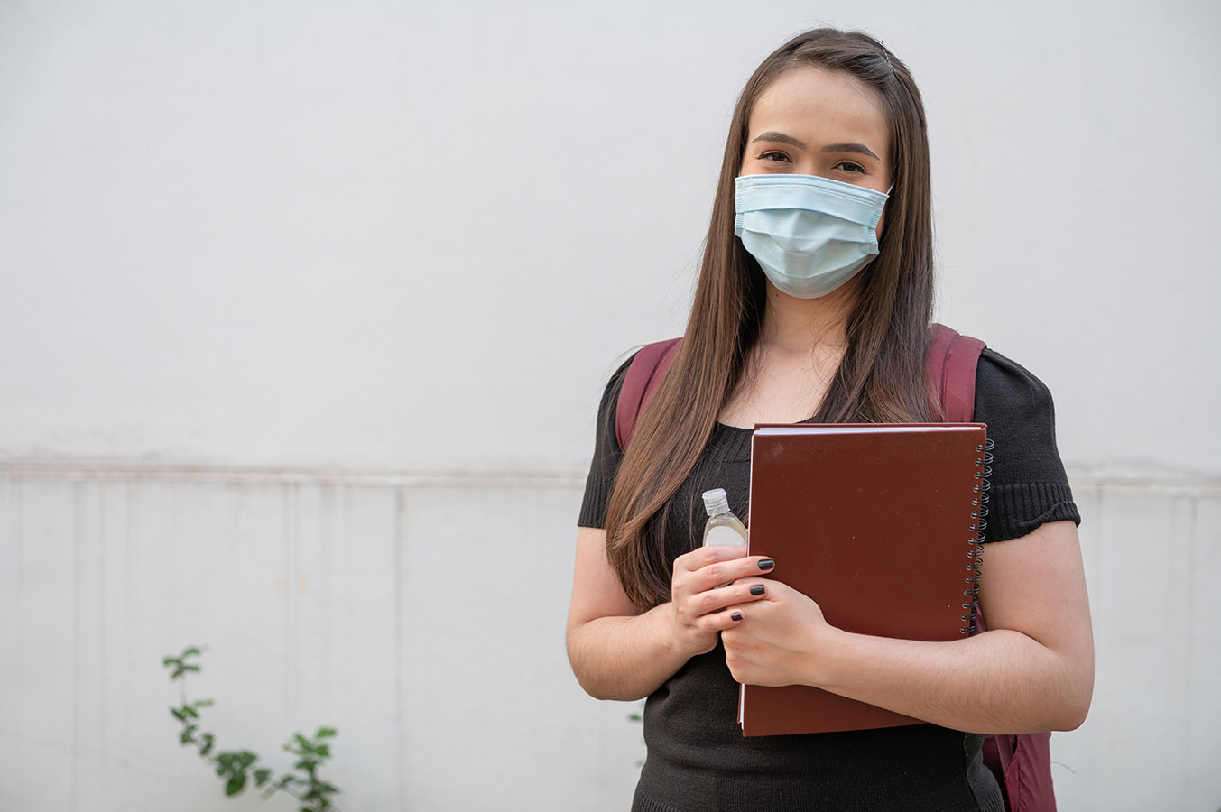 Teen wearing a face mask while standing outside.