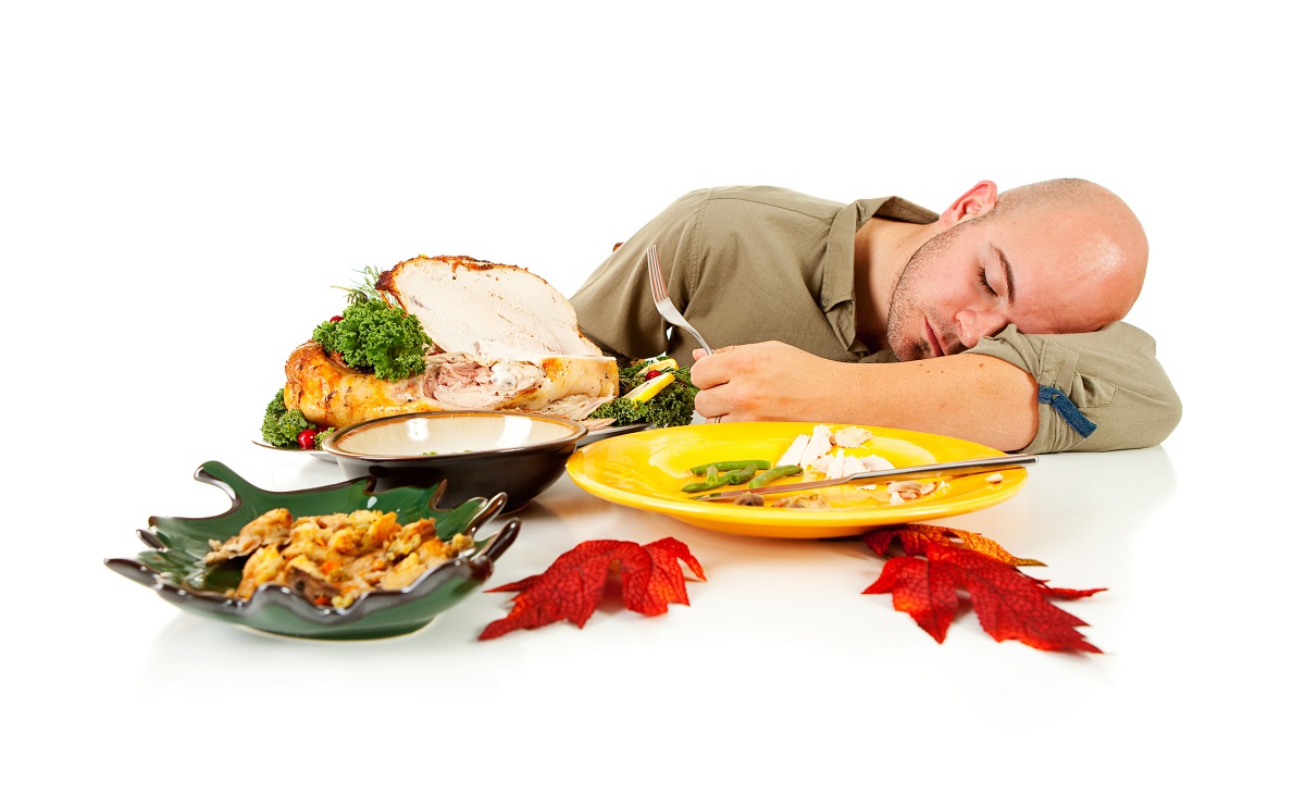 A man falls asleep at the table, amid what’s left of a turkey dinner.