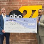 Two men are smiling and holding a big check for $214,000