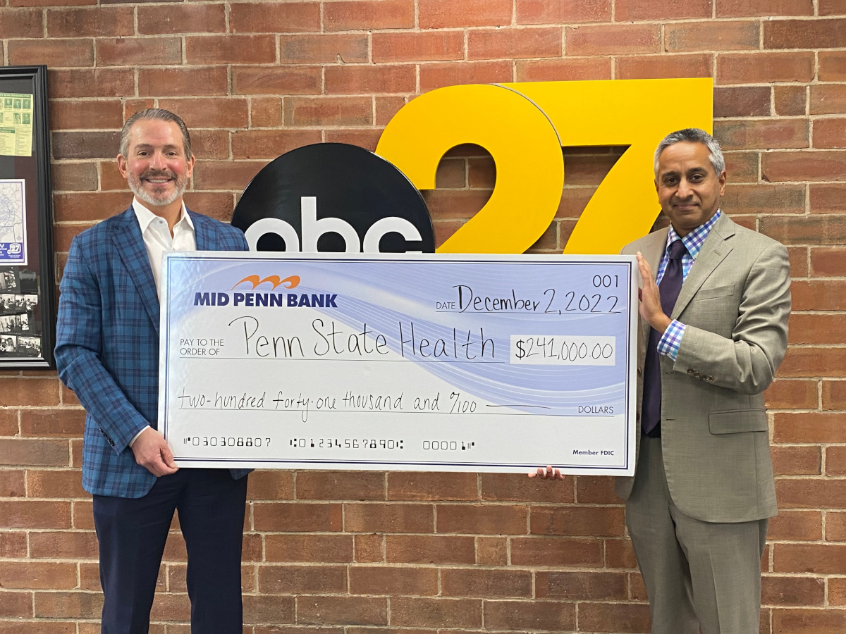 Two men are smiling and holding a big check for $214,000