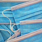Background of close up of multiple, light blue and white medical masks, protection against infectious disease.