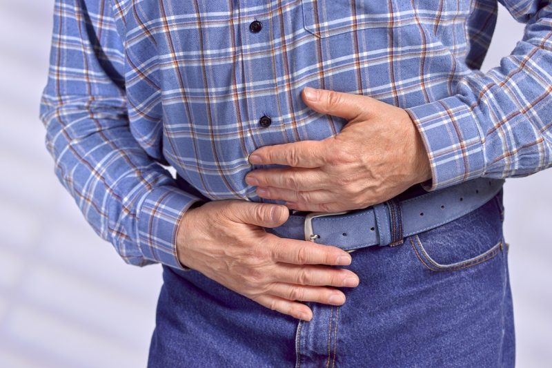 A man with stomach pain holds his stomach.