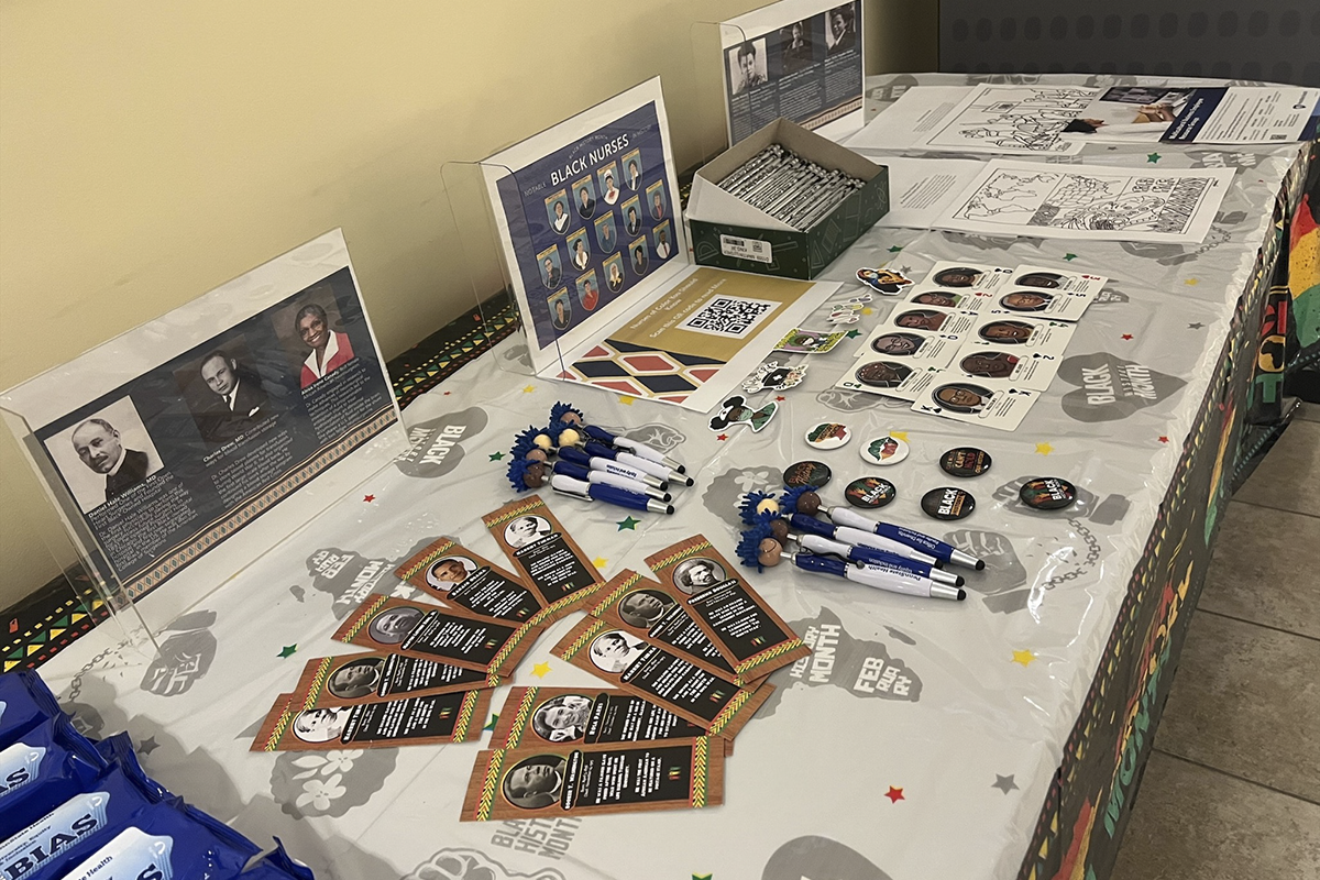 A display table containing Black History Month-themed items including flyers, slim jims, stickers and pens.