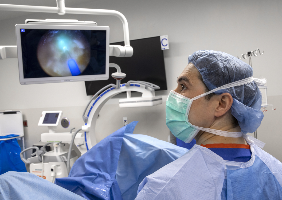 Dr. Jaime Herrera-Caceres looks up at a monitor as a draped patient lies on a procedure table.