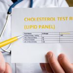 A physician uses a pen to point to a sheet of paper labeled “Cholesterol test result (Lipid panel).”