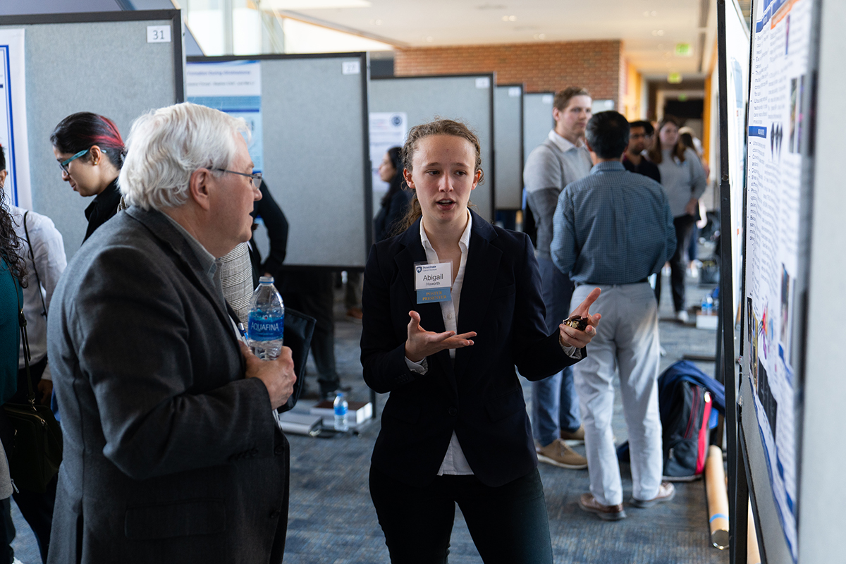 Graduate student explains her research to Raymond Hohl, director of Penn State Cancer Institute, during the Cancer Research Day