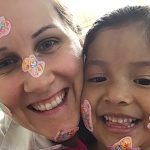 Woman and female child with stickers on their smiling faces.
