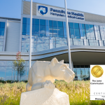 The statue of the Penn State Nittany lion sits next to the glass facade of Hampden Medical Center. Logos for the Joint Commission and the American Heart Association are superimposed.