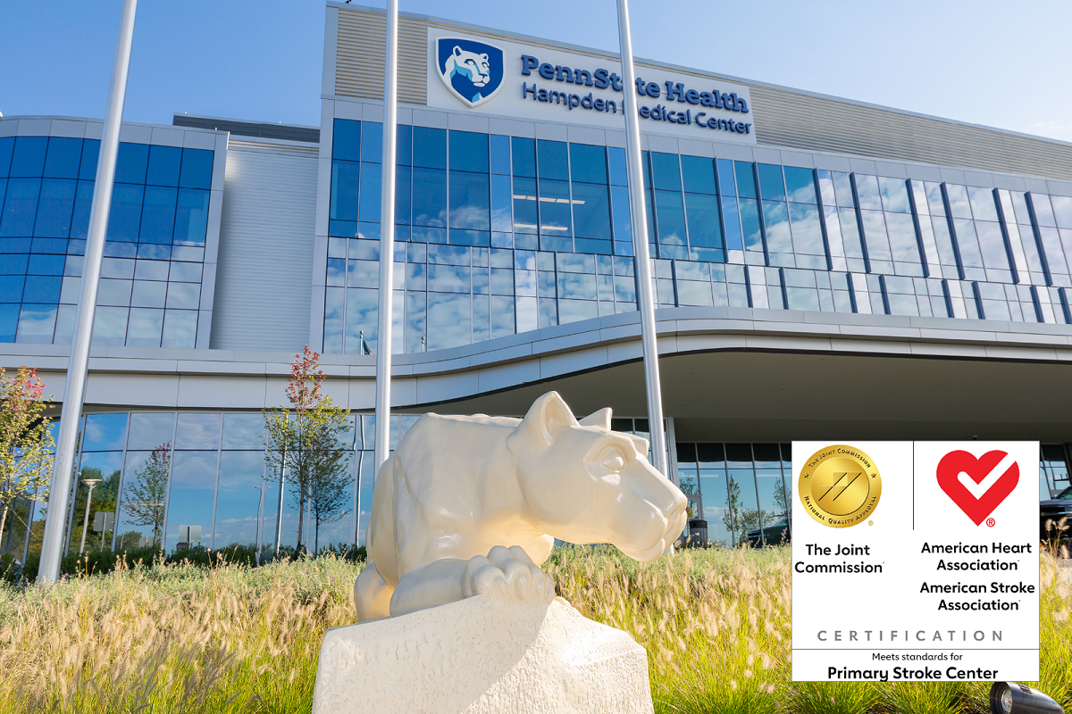 The statue of the Penn State Nittany lion sits next to the glass facade of Hampden Medical Center. Logos for the Joint Commission and the American Heart Association are superimposed.