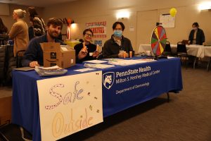 Chris Bazewicz, MD, dermatology resident, and Brianna Papoutsis and Jinpyo Hong sit at a table displaying skin care safety products during the SCOPE community outreach event on Saturday, Jan. 28 in Lykens.