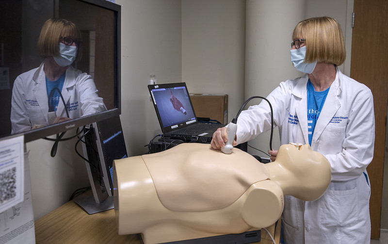 Elizabeth Sinz, MD, associate dean for clinical simulation and director of the Clinical Simulation Center, stands above a mannequin and performs a demonstration during an open house on Sept. 12, 2022.