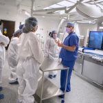A doctor dressed in scrubs shows several other people a new cardiac catheterization lab