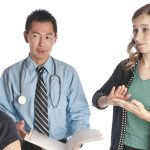 Young woman interpreting for a doctor and woman at the doctor's office using sign language