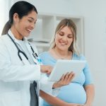 A doctor consults with a pregnant patient in a clinic.