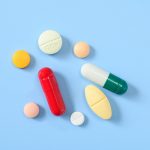 Flat lay of various pills and tablets on the blue background
