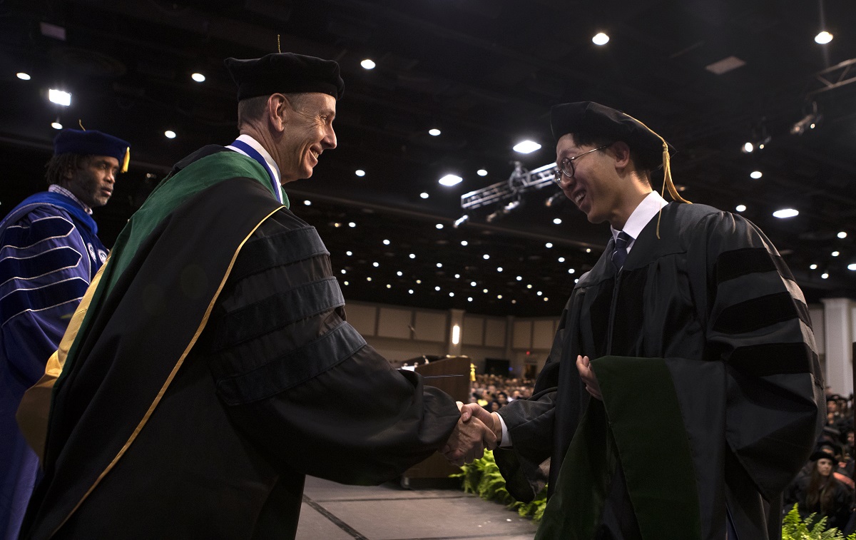 Dr. Kevin Black, interim dean at Penn State College of Medicine, shakes hands with Yongwook Dan.