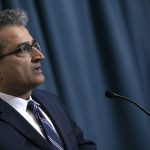 Viewed from the side, Thiru Annaswamy speaks in front of a microphone