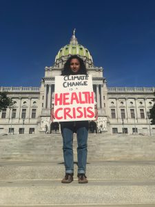 Natasha Sood stands on the steps of the capitol building in Harrisburg holding a sign that reads "Climate Change is a Health Crisis."