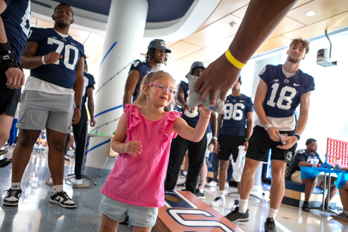 A young girl plays a bean bag game with members of the Penn State Football Team