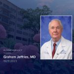 Portrait of the late Dr. Graham Jeffries in doctor's coat, on a gradient memorial background