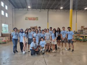 A large group of Penn Staters and international students in the Global Health Exchange Program volunteer at the Central Pennsylvania Food Bank in Harrisburg, helping to pack food boxes.