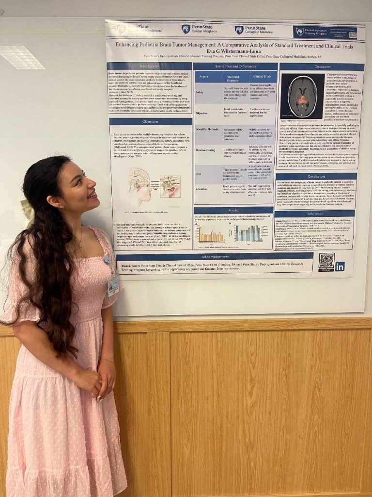 A woman stands to the left of a poster that depicts details of her clinical research internship experience.