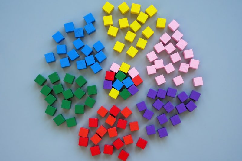 6 groups of cubes, each a pile of a single, distinct color, surround a multicolored pile that is made of up of cubes from each individual pile surrounding them.