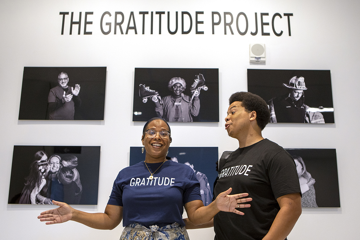 Two people stand in front of a wall of black-and-white photos.