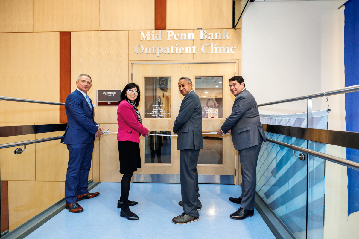 Four people cut a ribbon to dedicate the new name of a healthcare clinic