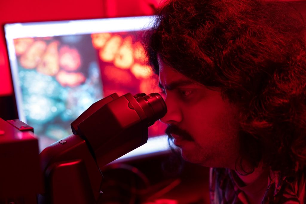 A man looks inside of a microscope. 