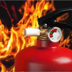 Top of fire extinguisher, flames in background.