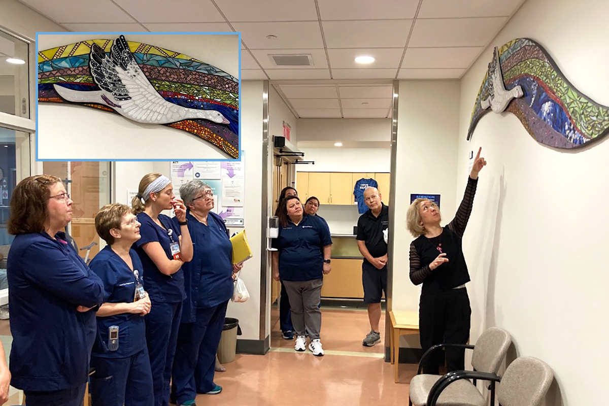 A woman points to art featuring good while several health care workers look on.