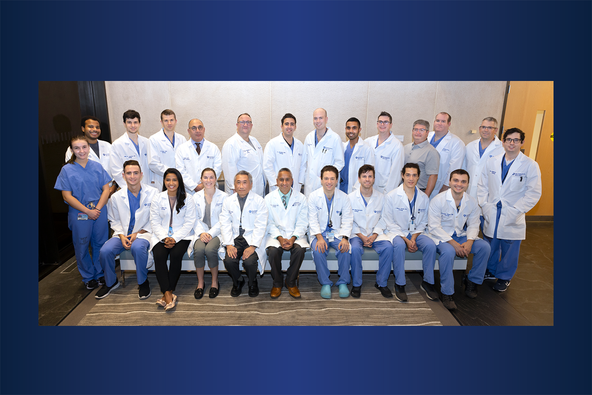A group of men and women in white coats and surgical scrubs pose for a photo.