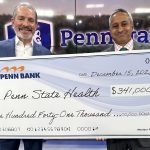 Two men pose for a photo with an oversized check in the amount of $341,000. A large Penn State Health logo is in the background.