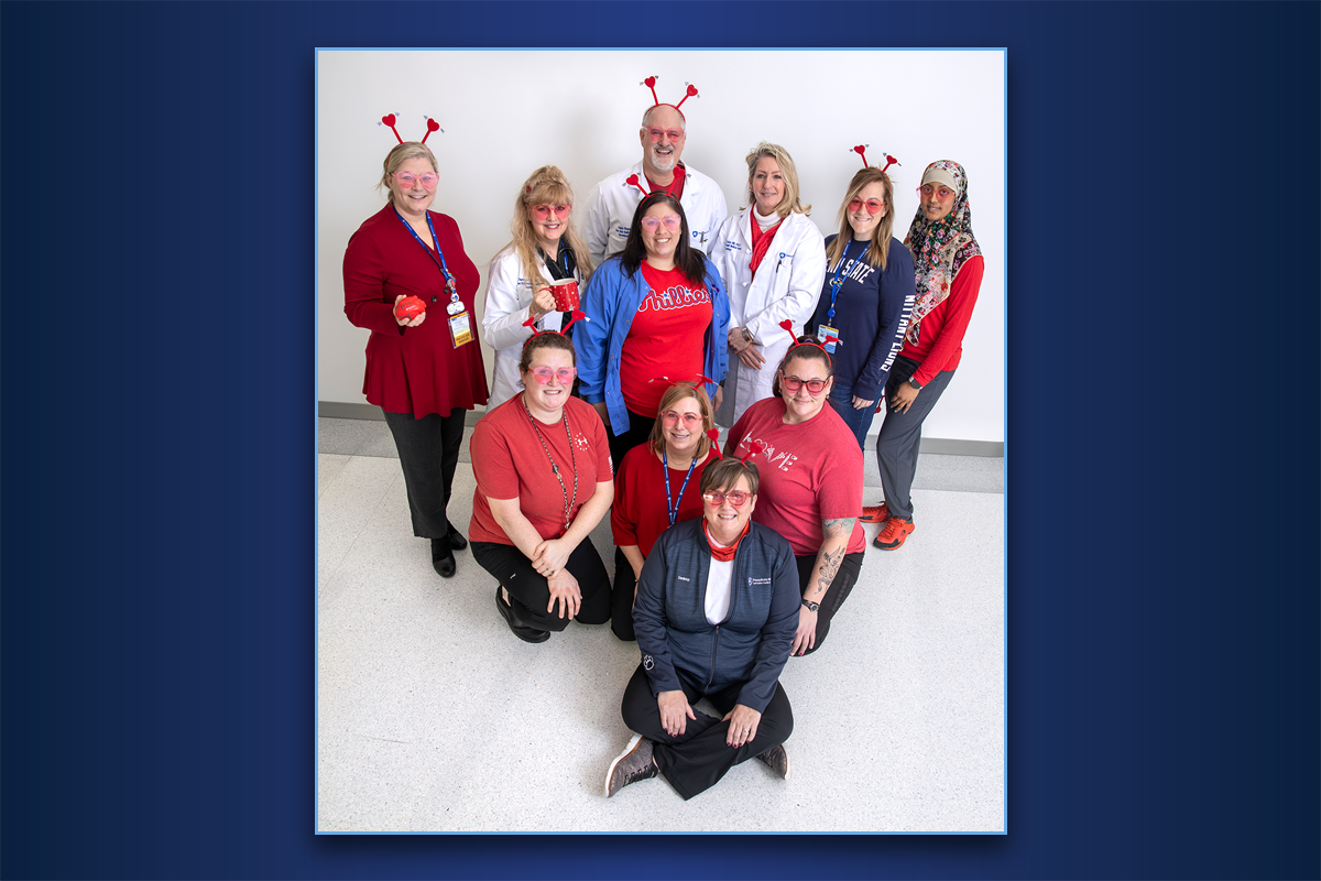 Eleven members of the Interventional Cardiology team at Penn State Health Lancaster Medical Center pose for a photo. They are wearing red to celebrate Wear Red Day. Three are wearing headbands with hearts as antennae.