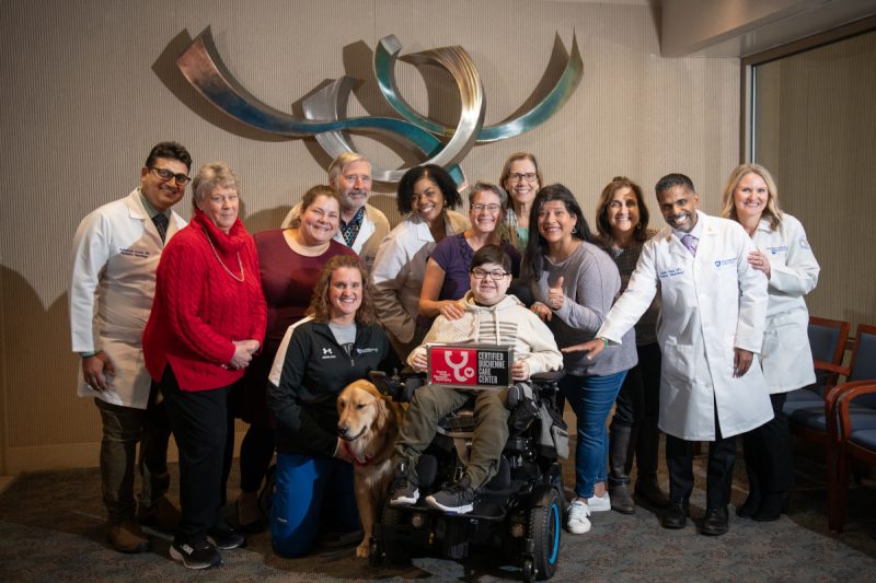 A pediatric muscular dystrophy care team poses for a photo with a patient and their family.