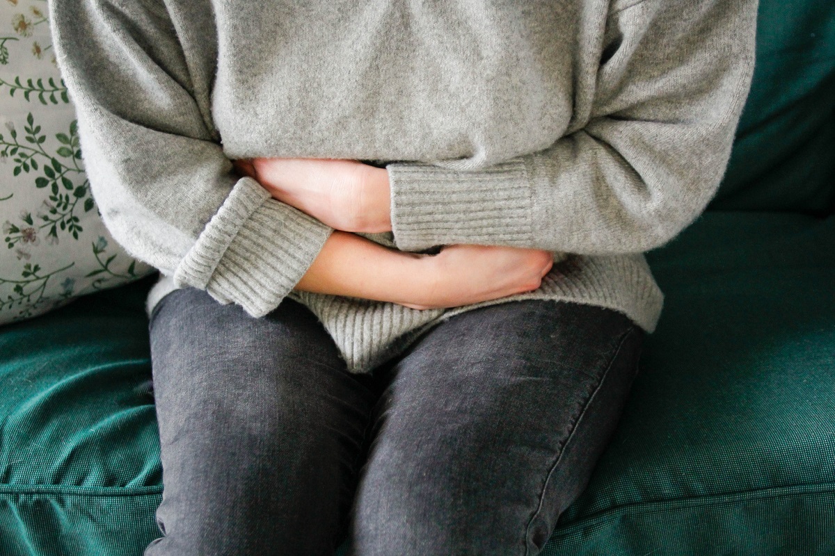 Close-up of a woman clutching her midsection due to apparent pain.