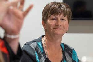A female case manager wearing a hospital badge looks at a woman seated next to her. The woman’s hands are gesturing as she speaks.