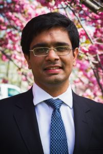 A head-and-shoulders image of Siddharth Sunilkumar, PhD, standing outside with a blossoming tree in the background