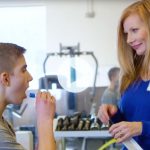 A teen takes a sample of his saliva while a researcher looks on