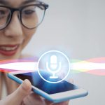 Image of a microphone logo levitating over an iPhone while a woman in glasses speaks into it.