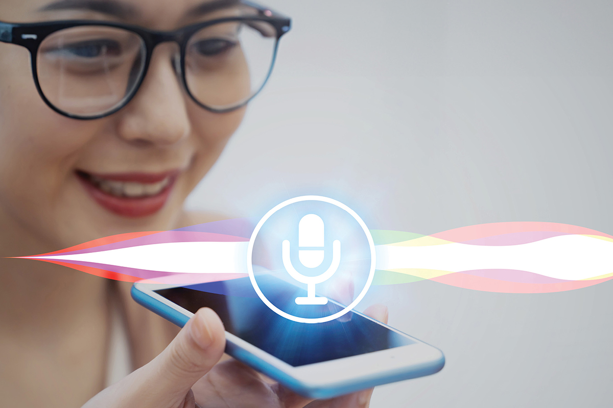 Image of a microphone logo levitating over an iPhone while a woman in glasses speaks into it.