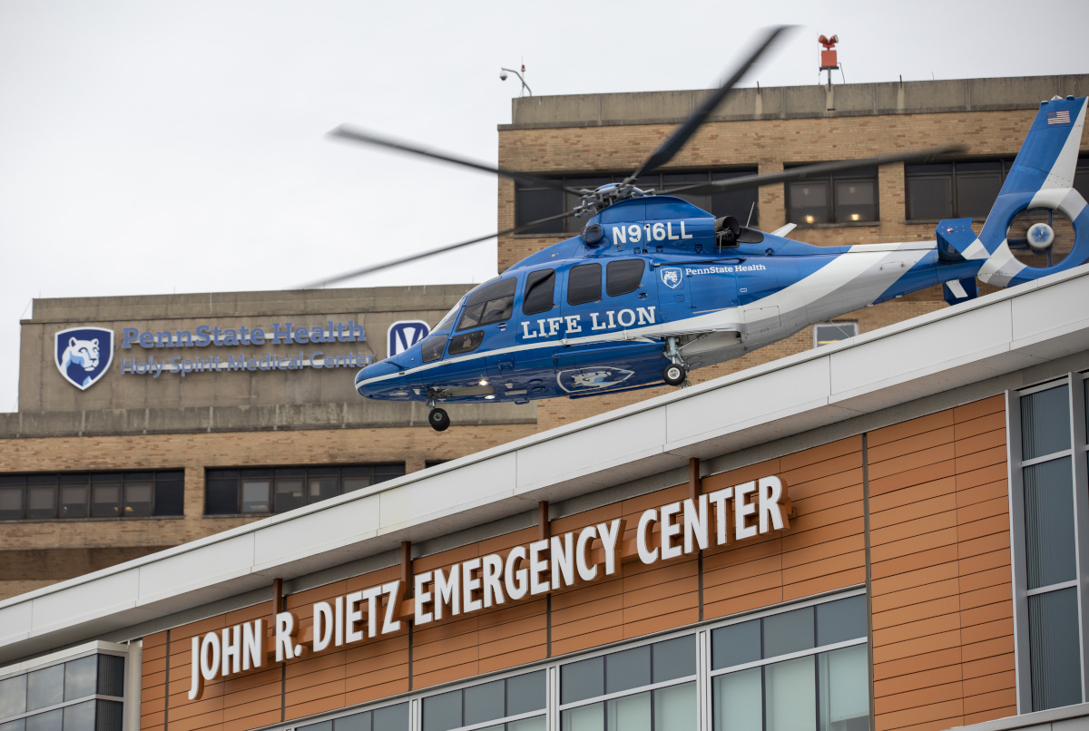 A helicopter lifts off from the roof of a building labeled 