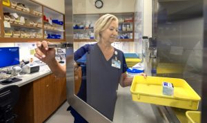 A pharmacist wearing navy blue scrubs at Penn State Health's Holy Spirit Medical Center, places a medication tray into a secure storage area.