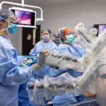 A physician and assisting clinicians perform a medical procedure using a robotic medical device.