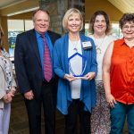 Five people pose with the United Way of Lebanon County Community Commitment Award trophy. They are standing in front of a stone fireplace.